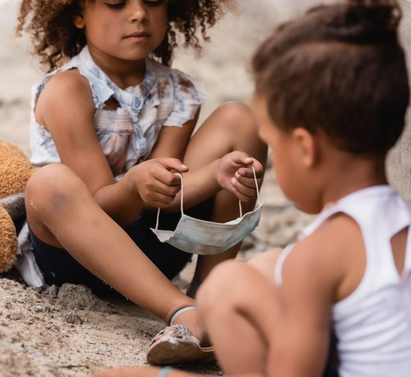 selective-focus-of-curly-african-american-child-holding-dirty-medical-mask-near-poor-brother-sitting.jpg